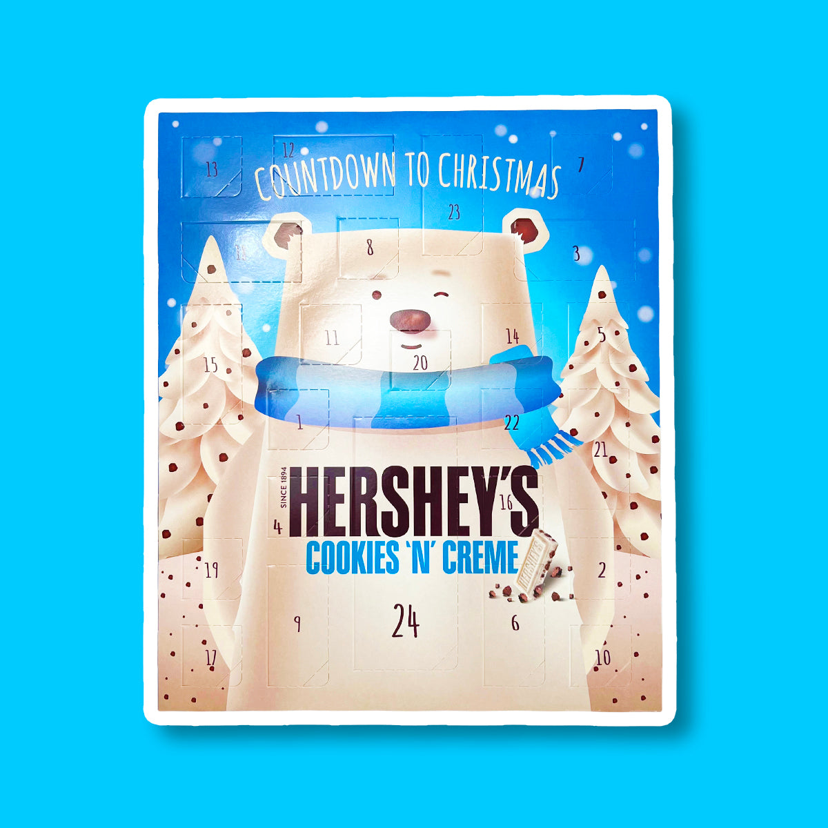 Un paquet bleu sur fond bleu avec un immense ours blanc qui fait un clin d’oeil et entouré de 2 sapins blanc. Chaque case à son nombre et sa forme