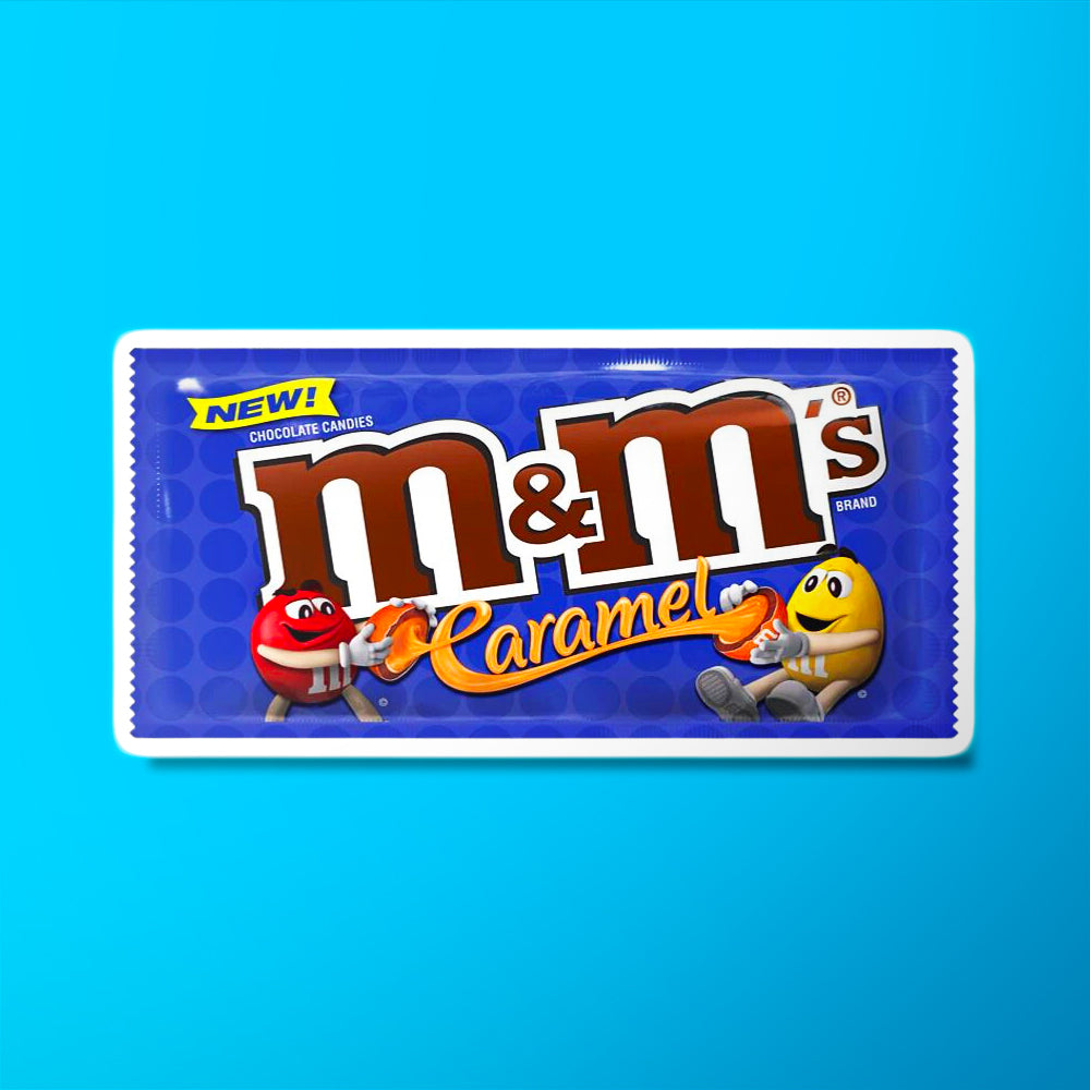 Un emballage bleu sur fond bleu avec 2 bonhommes M&M’s rouge et jaune qui tire un m&m’s coupé et il y a un fil de caramel orange 