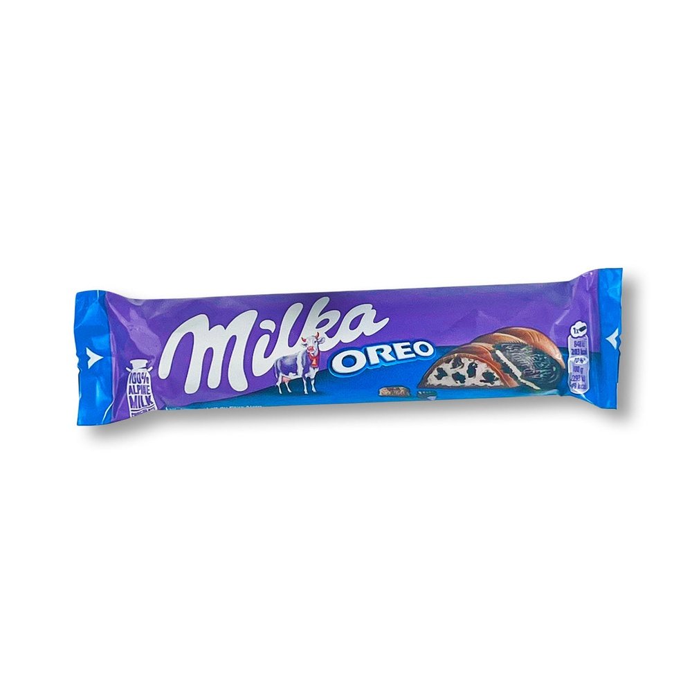 Un emballage mauve et bleu sur fond blanc à gauche il y a une vache blanche et rose, à gauche du chocolat fourré avec une crème blanche rempli de petits morceaux de biscuits noirs