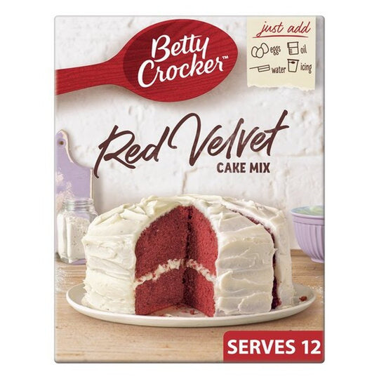 Un carton sur fond blanc avec un gâteau blanc à l’intérieur rouge sur une assiette blanche qui est sur une table en bois avec à l’arrière un mur blanc