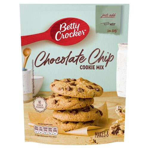Un emballage sur fond blanc avec 4 cookies sur du papier sulfurisé qui est sur une table en bois avec à l’arrière un mur vert pâle