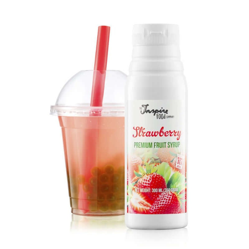A gauche un gobelet et un paille orange avec une thé rosé avec des billes vertes. Et à droite une bouteille blanche avec des fraises, le tout sur fond blanc