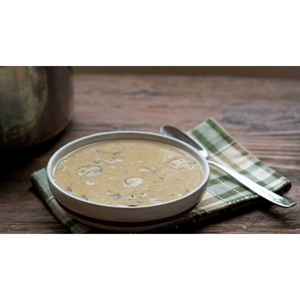 Un bol gris sur une table en bois sombre avec un soupe aux champignons et à côté une cuillère