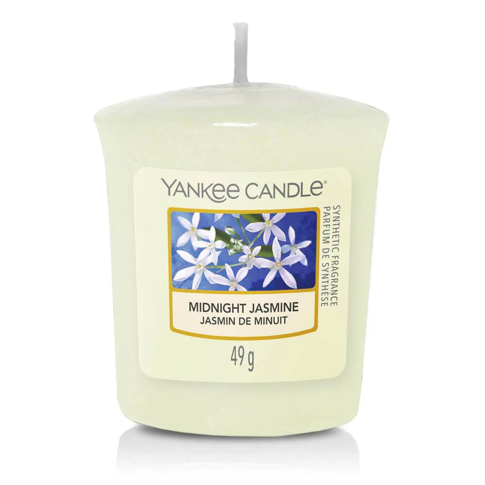 Une bougie blanc cassé avec sa mèche blanche et une étiquette avec des fleurs de jasmin blanches. Le tout sur fond blanc