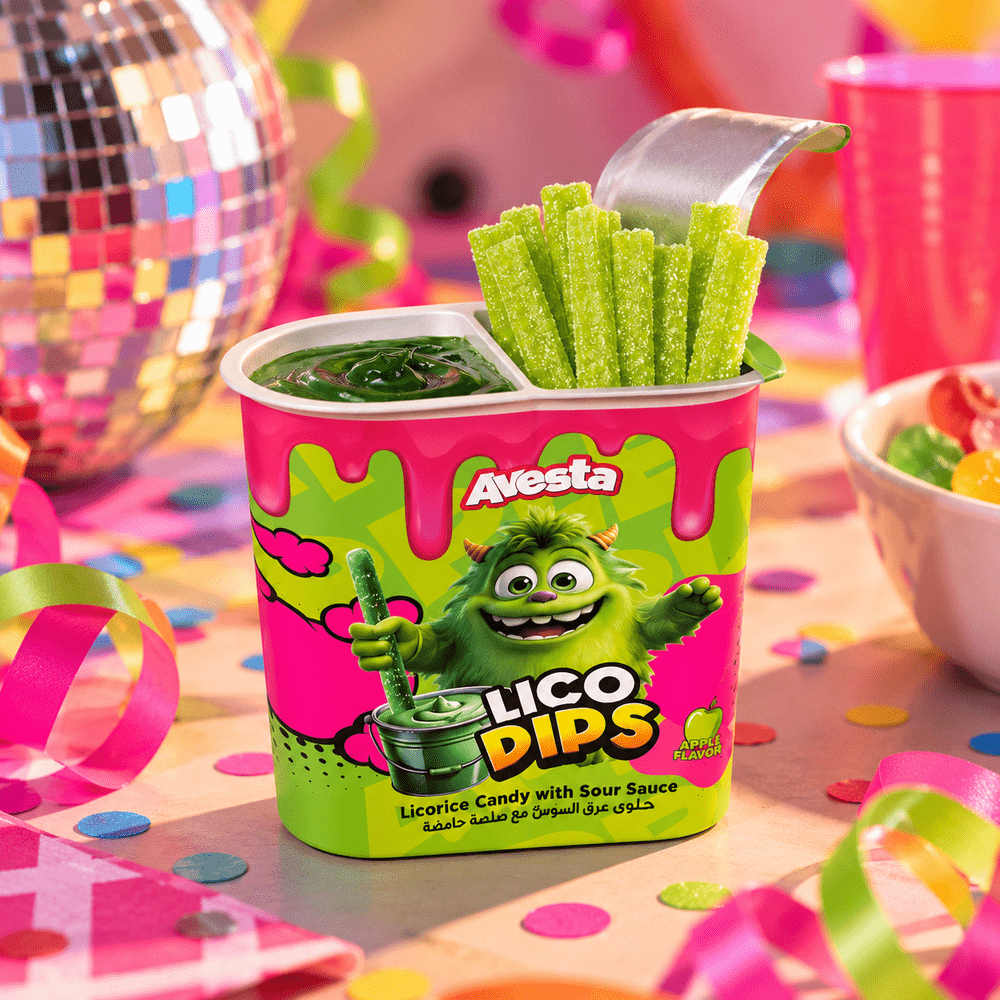 Pot Avesta Lico Dips Green Apple, bâtonnets de réglisse verte avec sauce acidulée à la pomme, dans un décor festif rose et vert.