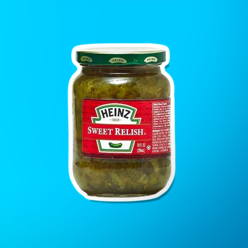 Un bocal transparent avec un capuchon vert, on y voit une sauce verte et une étiquette rouge avec un cornichon au centre. Le tout sur fond bleu