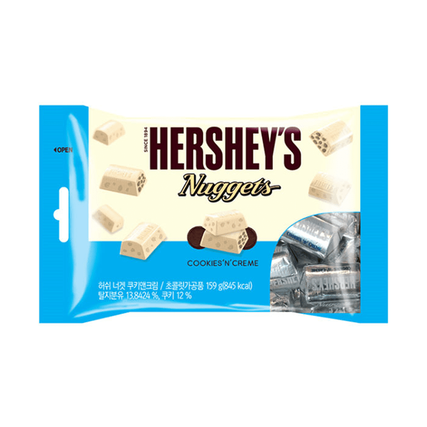 Un emballage bleu et blanc sur fond blanc avec des morceaux de chocolats blancs