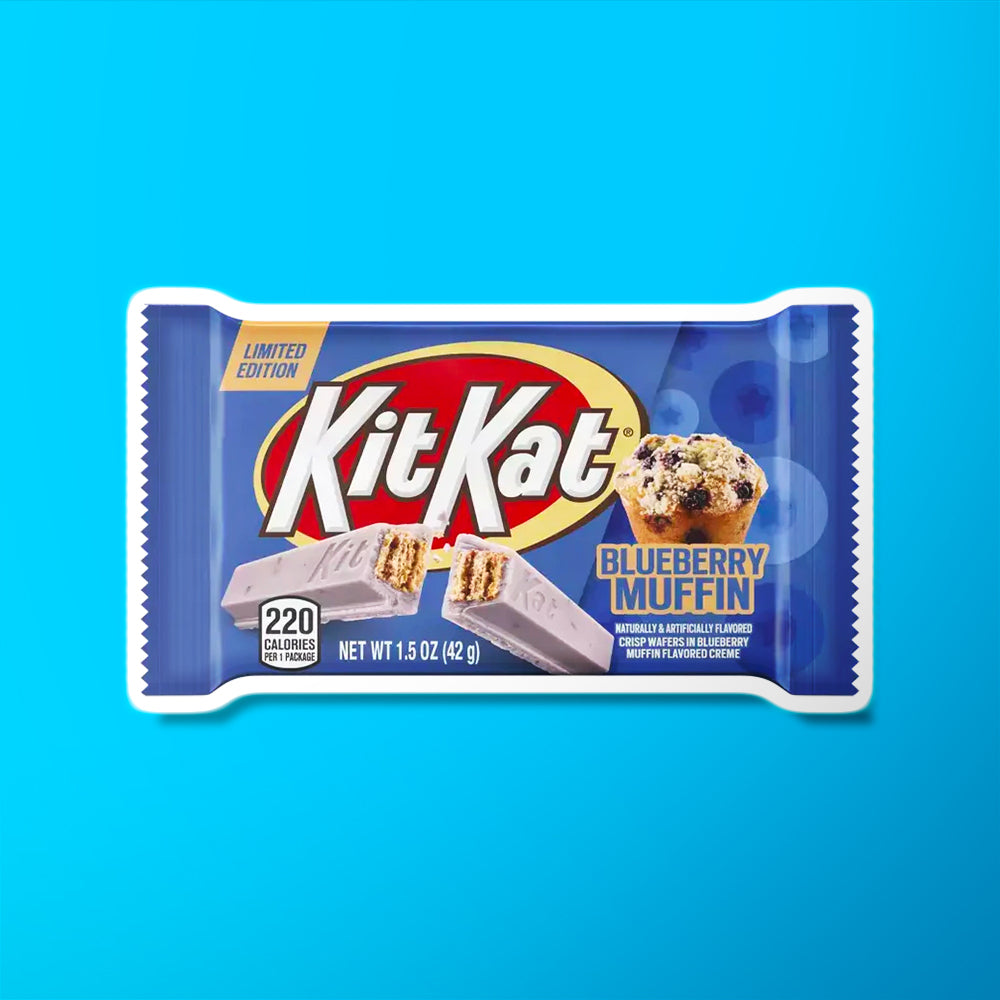 Un emballage bleu avec au centre il y a un biscuit en bâtonnet violet pâle et sur le coté une part de muffin avec des morceaux de bleuets noirs. Le tout sur fond bleu