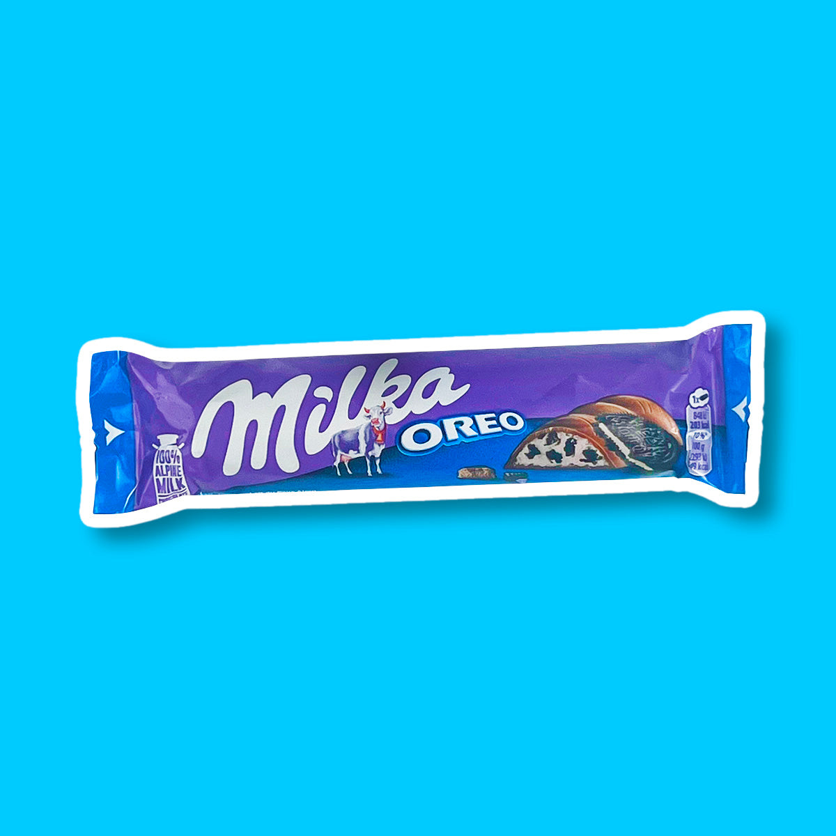 Un emballage mauve et bleu sur fond bleu à gauche il y a une vache blanche et rose, à gauche du chocolat fourré avec une crème blanche rempli de petits morceaux de biscuits noirs
