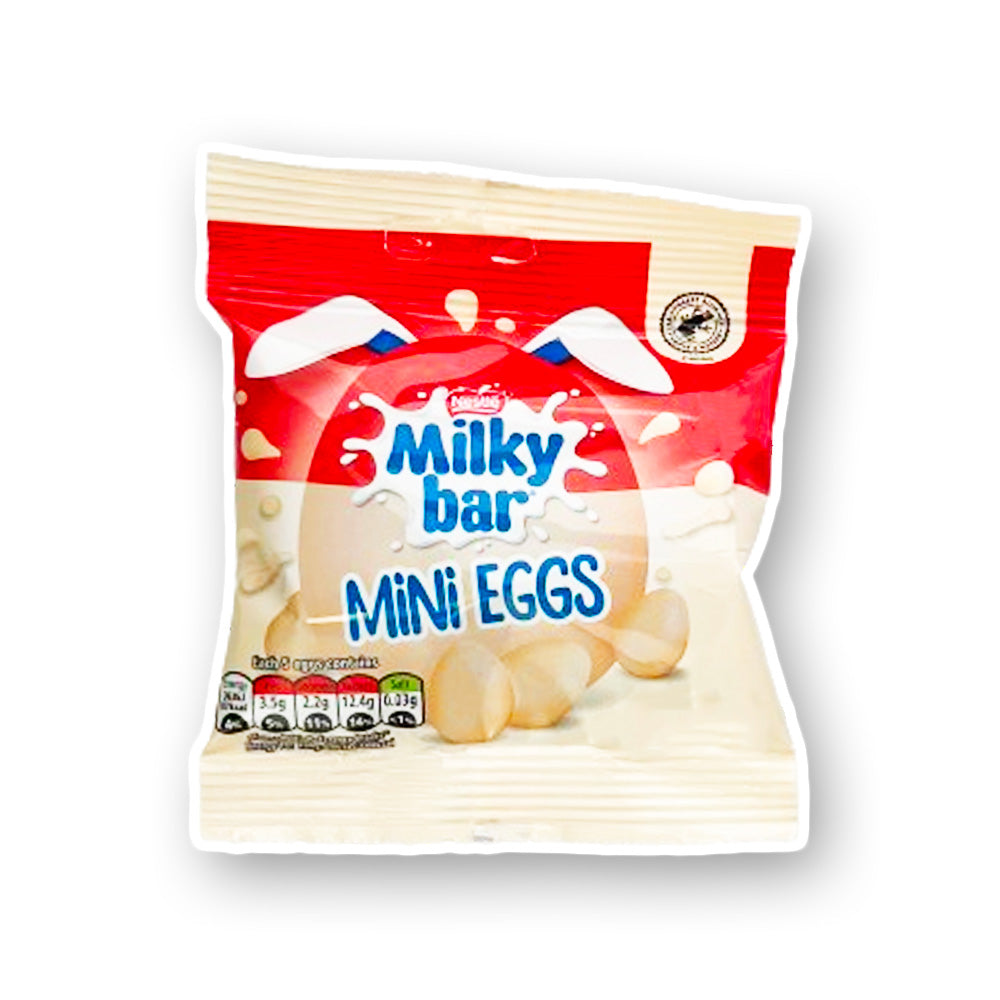 Un emballage beige avec une bande rouge au-dessus, au centre on y voit un grand oeuf avec des oreilles de lapin blanc et en dessous 3 petits oeufs au chocolat blanc. Le tout sur fond blanc