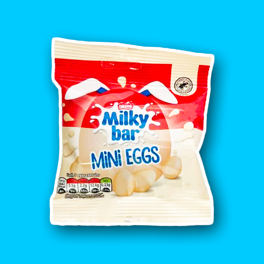 Un emballage beige avec une bande rouge au-dessus, au centre on y voit un grand oeuf avec des oreilles de lapin blanc et en dessous 3 petits oeufs au chocolat blanc. Le tout sur fond bleu