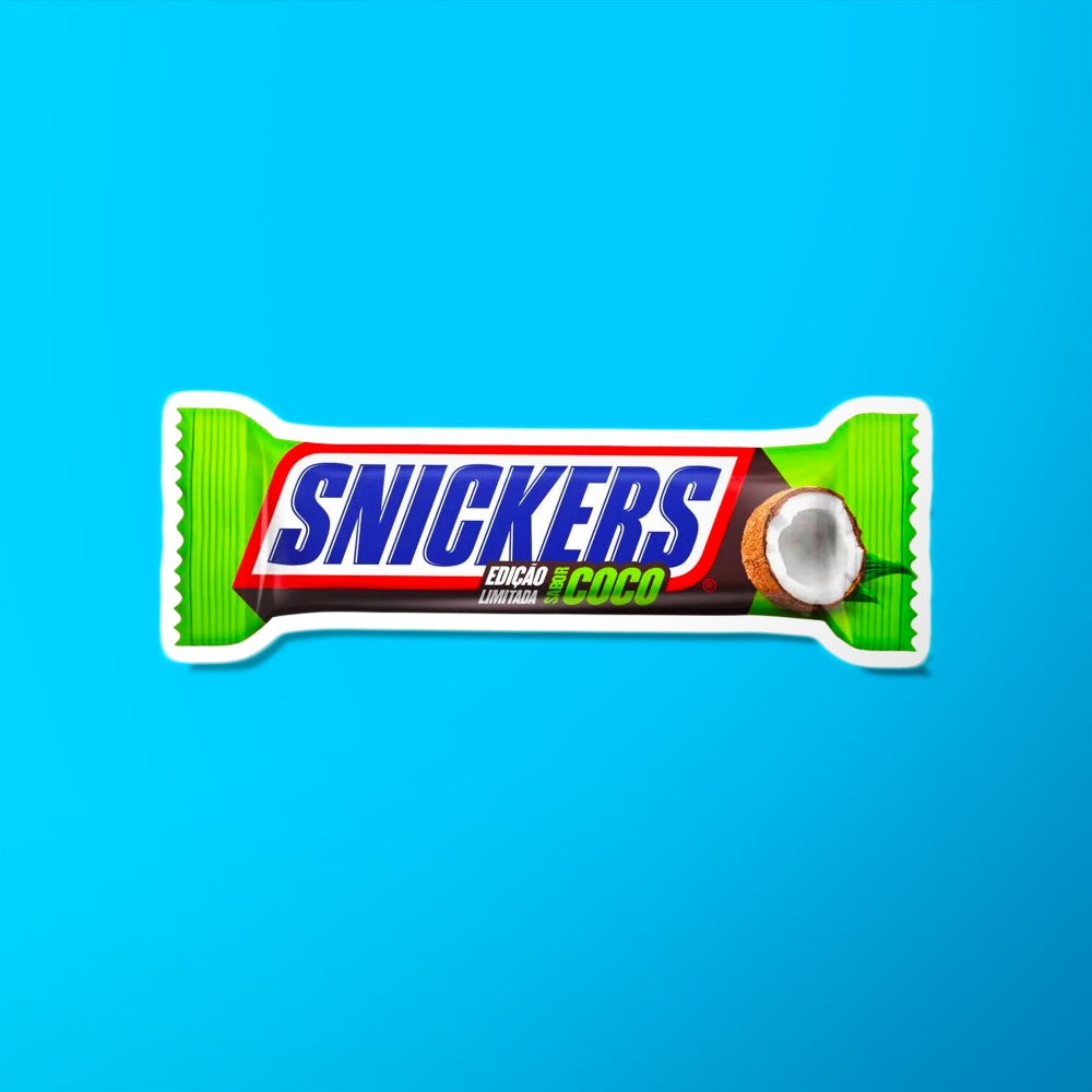 Un emballage vert sur fond bleu avec au centre écrit « Snickers » en bleu et sur le côté droit il y a une demi noix de coco