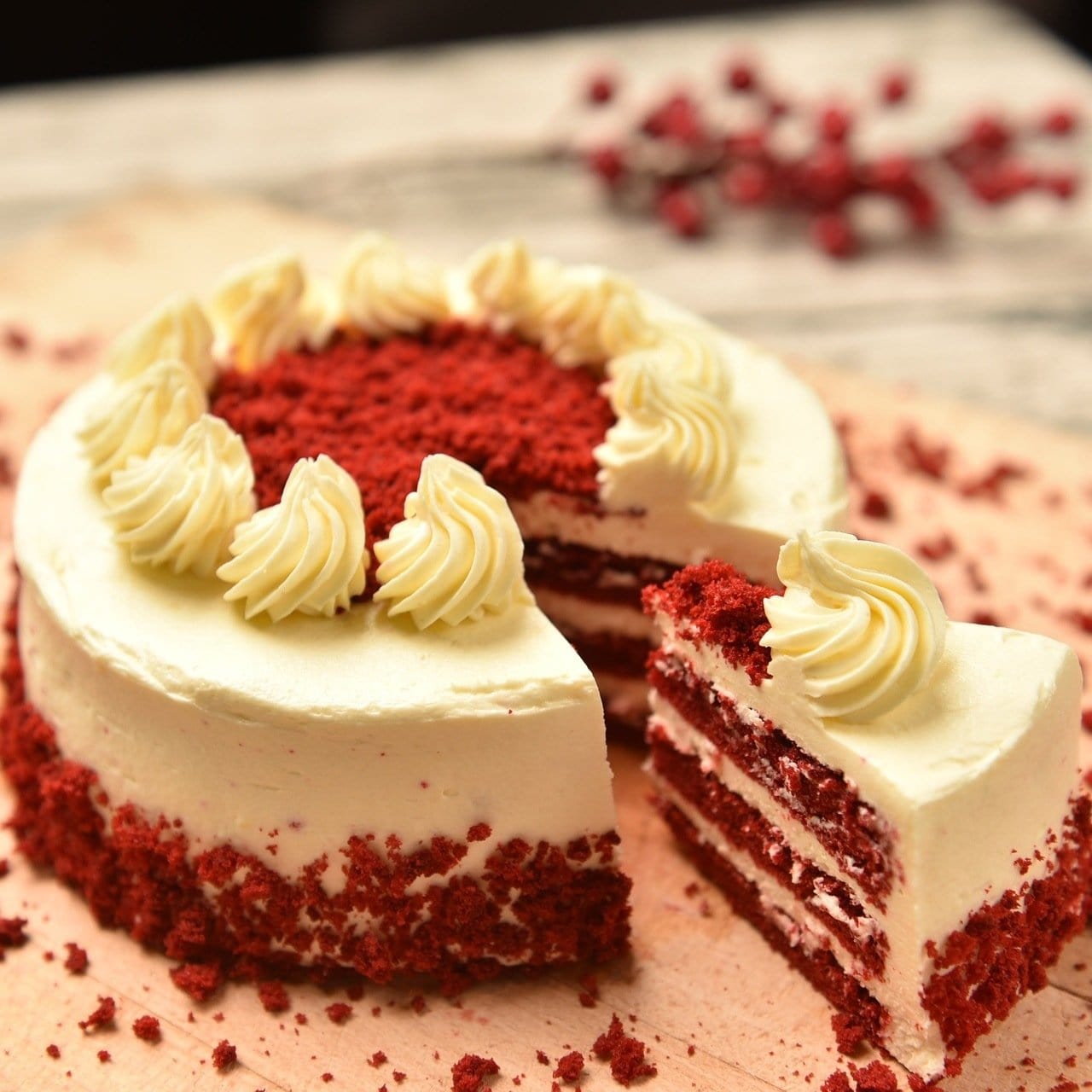 Un gâteau blanc à l’intérieur rouge sur une planche en bois. Sur le dessus du gâteau des décorations avec de la crème chantilly