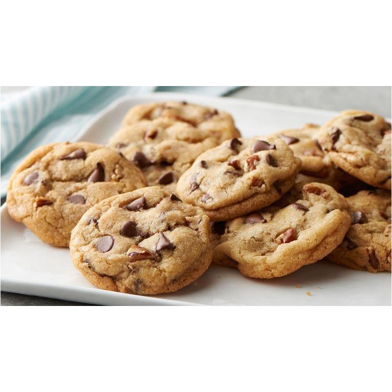 Des cookies aux pépites de chocolat sur une assiette blanche et à l'arrière une serviette blanche et bleue