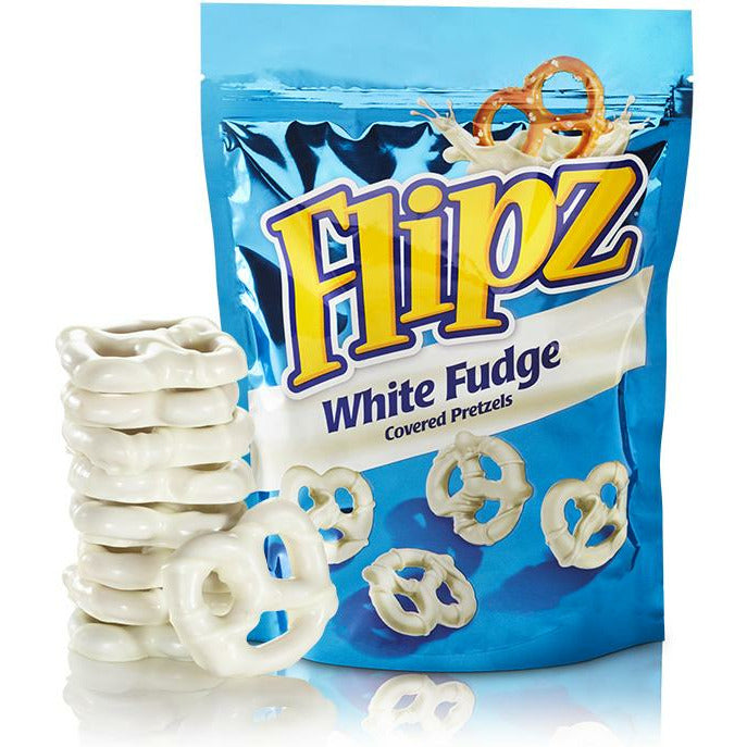 Un emballage bleu sur fond blanc, avec 5 petits bretzels blancs dont un en haut à gauche avec un éclaboussement de caramel blanc. A gauche du paquet se trouve 8 Flipz empilés les uns sur les autres