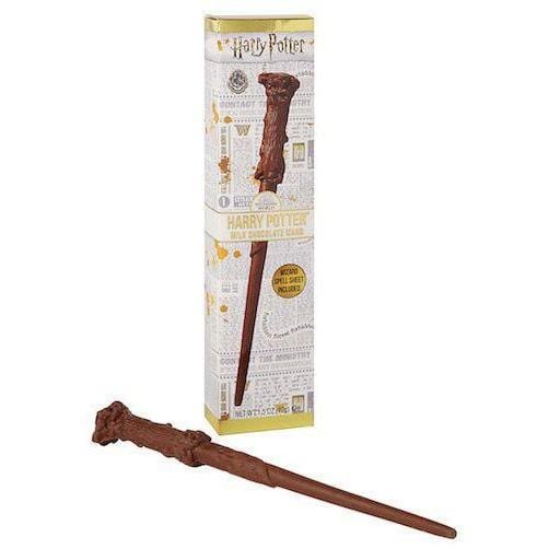 Un carton blanc sur fond blanc avec les motifs d’un journal et dessus la baguette magique d’Harry Potter en chocolat. Devant l’emballage, la baguette en chocolat