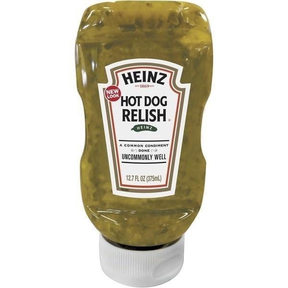 Une bouteille transparente d’une sauce verte gélatineuse avec de petits morceaux de cornichons, le tout sur fond blanc