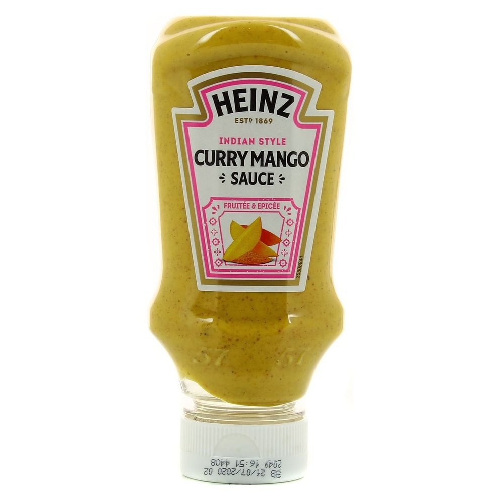 Une bouteille transparente d’une sauce jaune, un capuchon blanc et une étiquette blanche au centre avec des morceaux de mangue et des épices. Le tout sur fond blanc