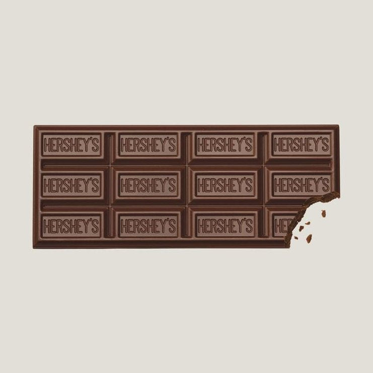 Une tablette de chocolat au lait sur fond blanc avec des inscriptions « Hershey’s » sur chaque carré, en bas à droite il y a un morceau qui a été croqué
