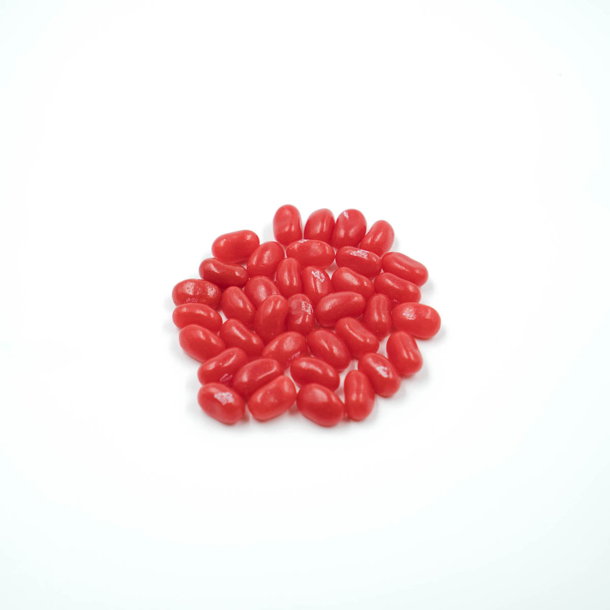 Un petit tas de bonbons en formes d'haricots rouges, sur fond blanc