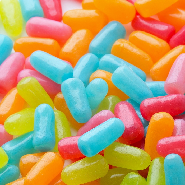 Des bonbons en formes de pilules jaune, rouge, verte, orange et bleu
