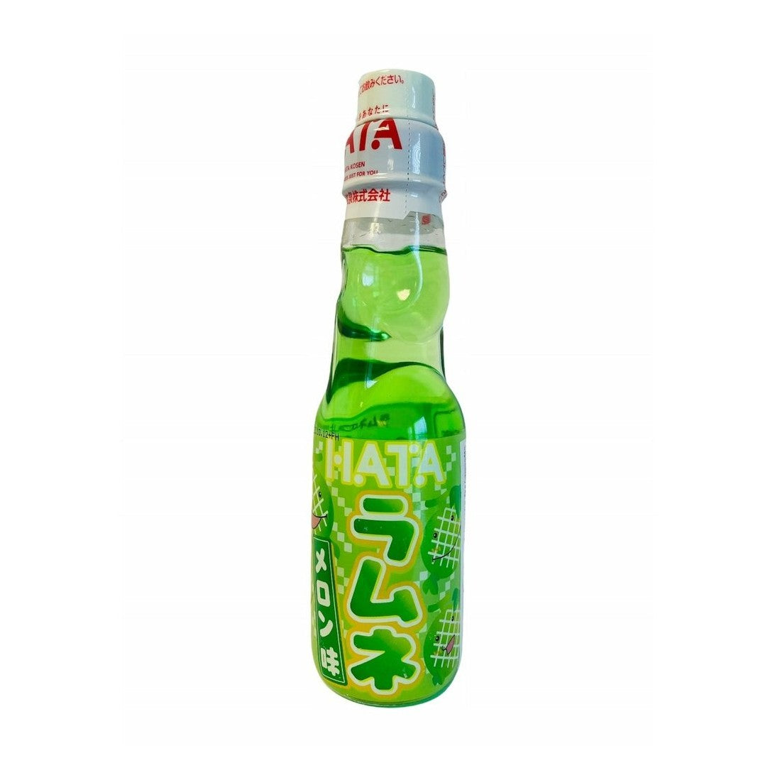 Une bouteille transparente sur fond blanc avec une boisson légèrement verte, il y a une étiquette verte sur la moitié basse de la bouteille. Il y a des melons qui sourient