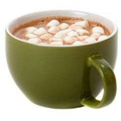 Une tasse verte avec du chocolat chaud et de mini marshmallows blanc, sur fond blanc