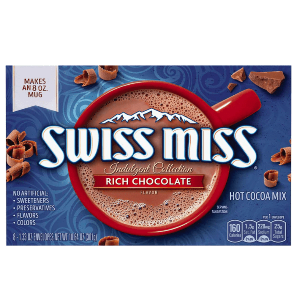 Un emballage bleu sur fond blanc avec une tasse rouge vue d’en haut, elle est remplie de cacao chaud et autour il y a des petits copeaux de chocolat 