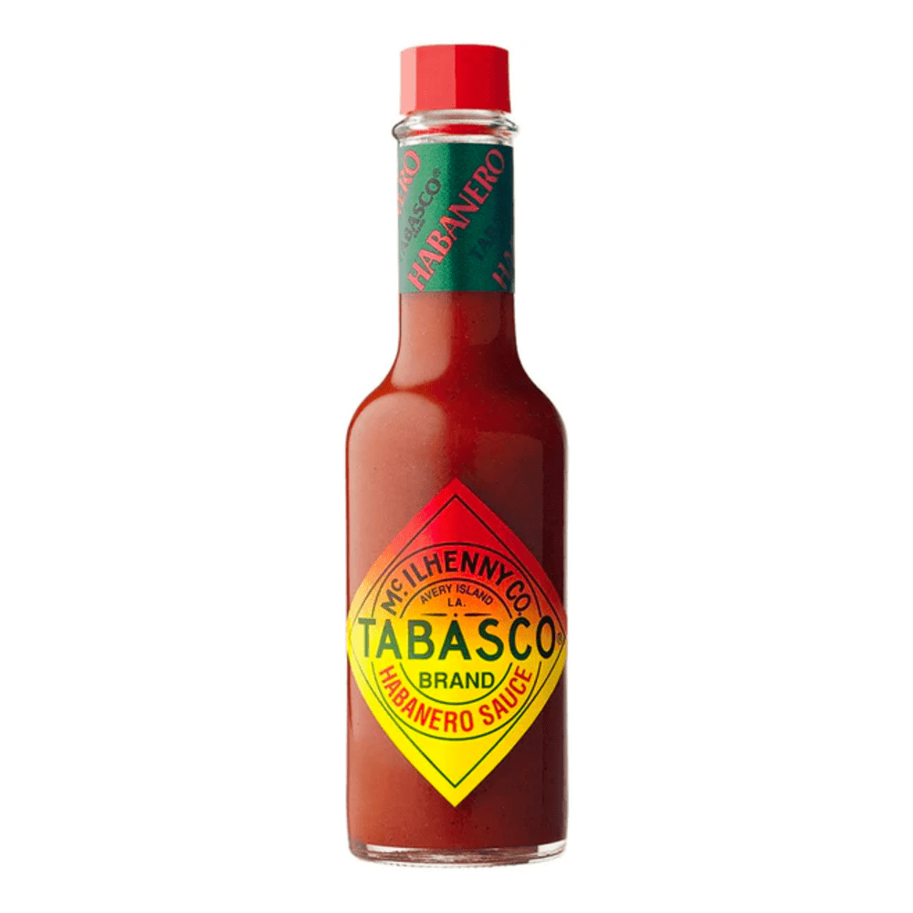 Une bouteille en verre remplie d’une sauce rouge, un capuchon rouge et une étiquette rouge et jaune avec des écrits verts. Le tout sur fond blanc