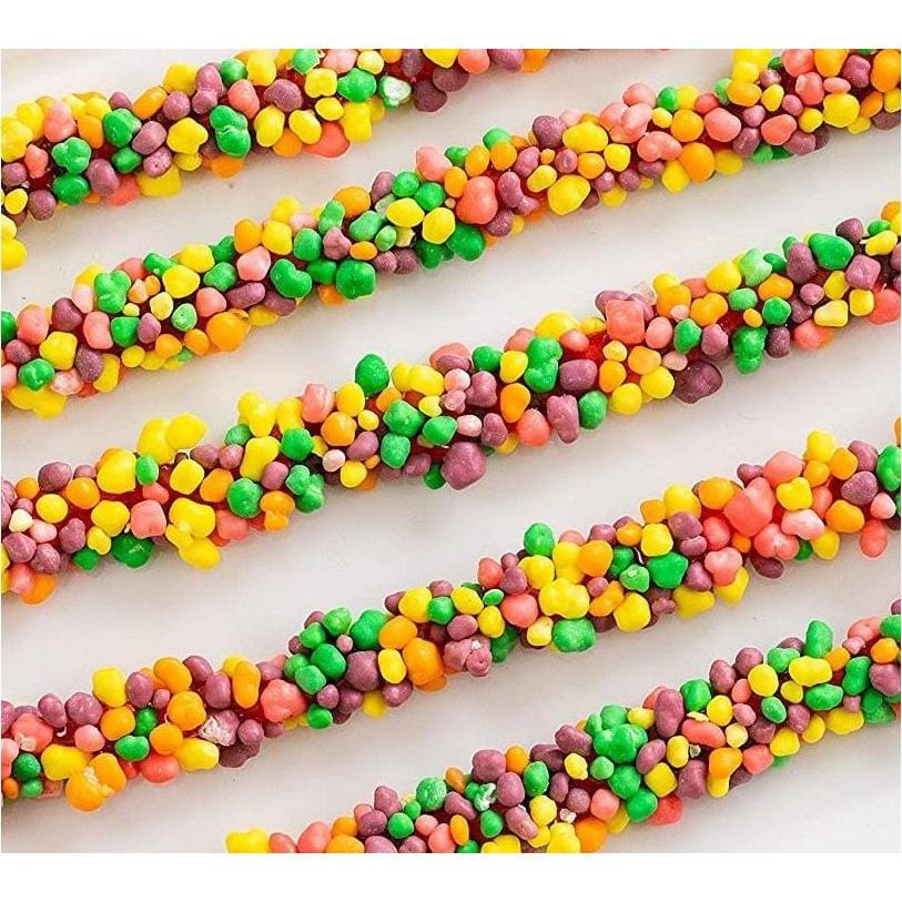 Plusieurs bonbons de perles colorés long et des personnages rose, orange, jaune et mauve. Le tout sur une table blanche